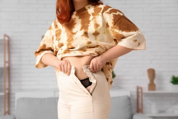 Image of woman trying to do her trousers up after pregnancy weight gain Barnsley